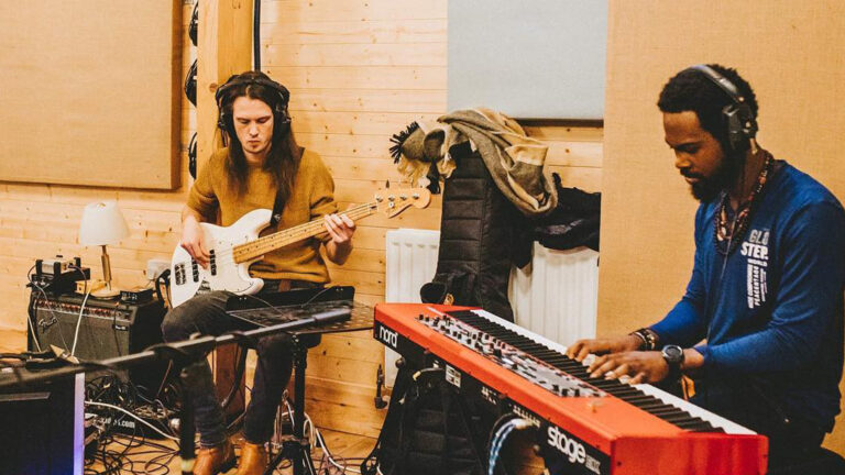 GiwHa playing keyboards with headphones on whilst recording with a backing band